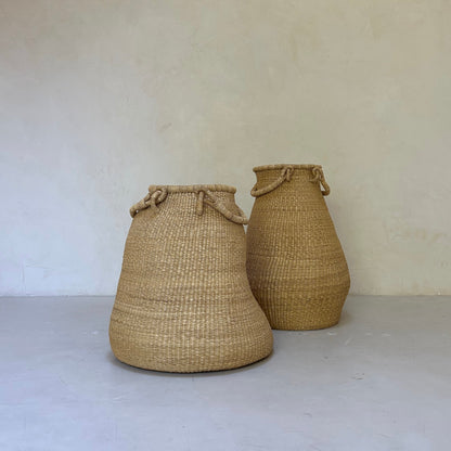 Large pear-shaped handwoven baskets, each with two handles that are designed to sit on the floor. Made in Ghana from local sustainable grass.