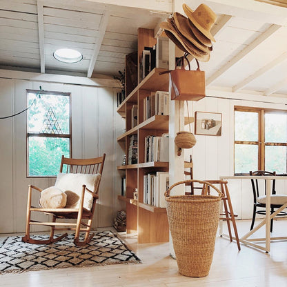 Large oversized African basket with handles, placed in a living area with book shelves.