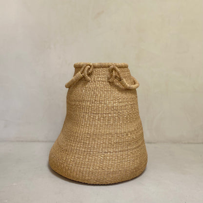 Large pear-shaped handwoven baskets, with two handles that are designed to sit on the floor. Made in Ghana from local sustainable grass.