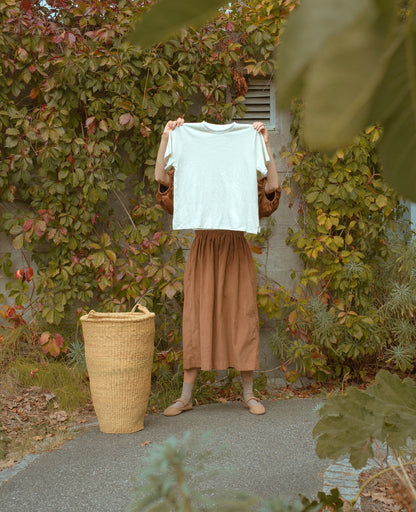 Hand woven basket for laundry. Woman holding up a t-shirt.