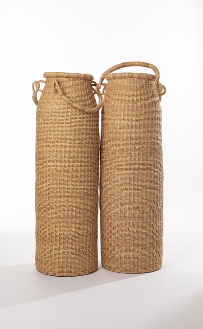 A tall column-shaped baskets with two handles. More sculpture than storage, these handwoven baskets are made in Ghana from natural materials.