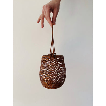 A small smoked bamboo basket with handle. Handcrafted and hand woven by Japanese artist Mie Kodama.