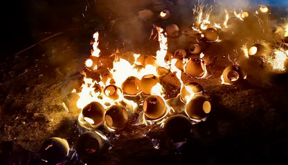 Showing how the ceramic base of the Ash Lamp is fired in a large pit.