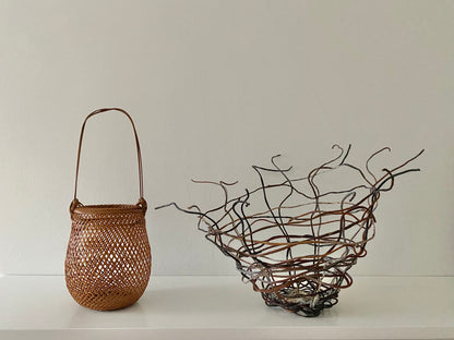 A small smoked bamboo basket handcrafted and hand woven by Japanese artist Mie Kodama. Shown next to an open weave basket.