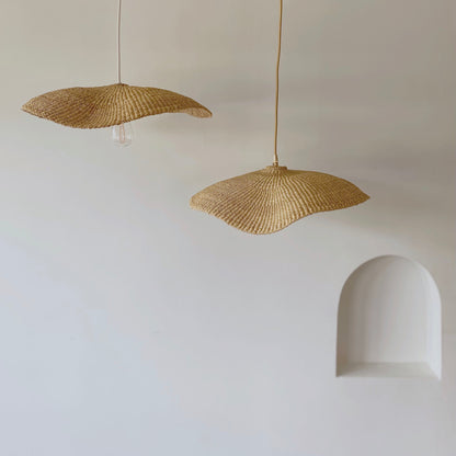 Showing two Our Fawn light shades. Handwoven from sustainable elephant grass in Ghana. Their wide and floating shape are striking in any living space, especially in bedrooms or over dining tables.