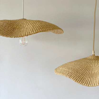 Two Fawn light shade handwoven from sustainable elephant grass in Ghana. Their wide and floating shape are striking in bedrooms or over dining tables.