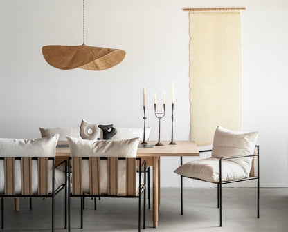 The hand woven, natural colored Fawn pendant light is shown over a dining table and chairs.