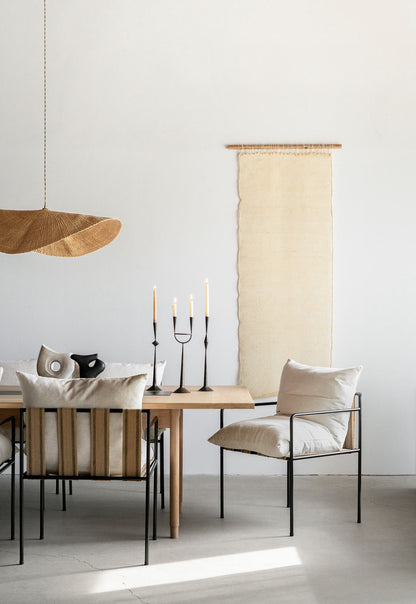 The hand woven, natural colored Fawn pendant light is shown over a dining table and chairs.