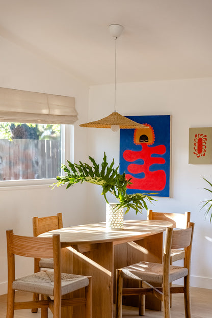 Sunhat light shade over a dining table. Light shade is woven into a shallow cone shape.