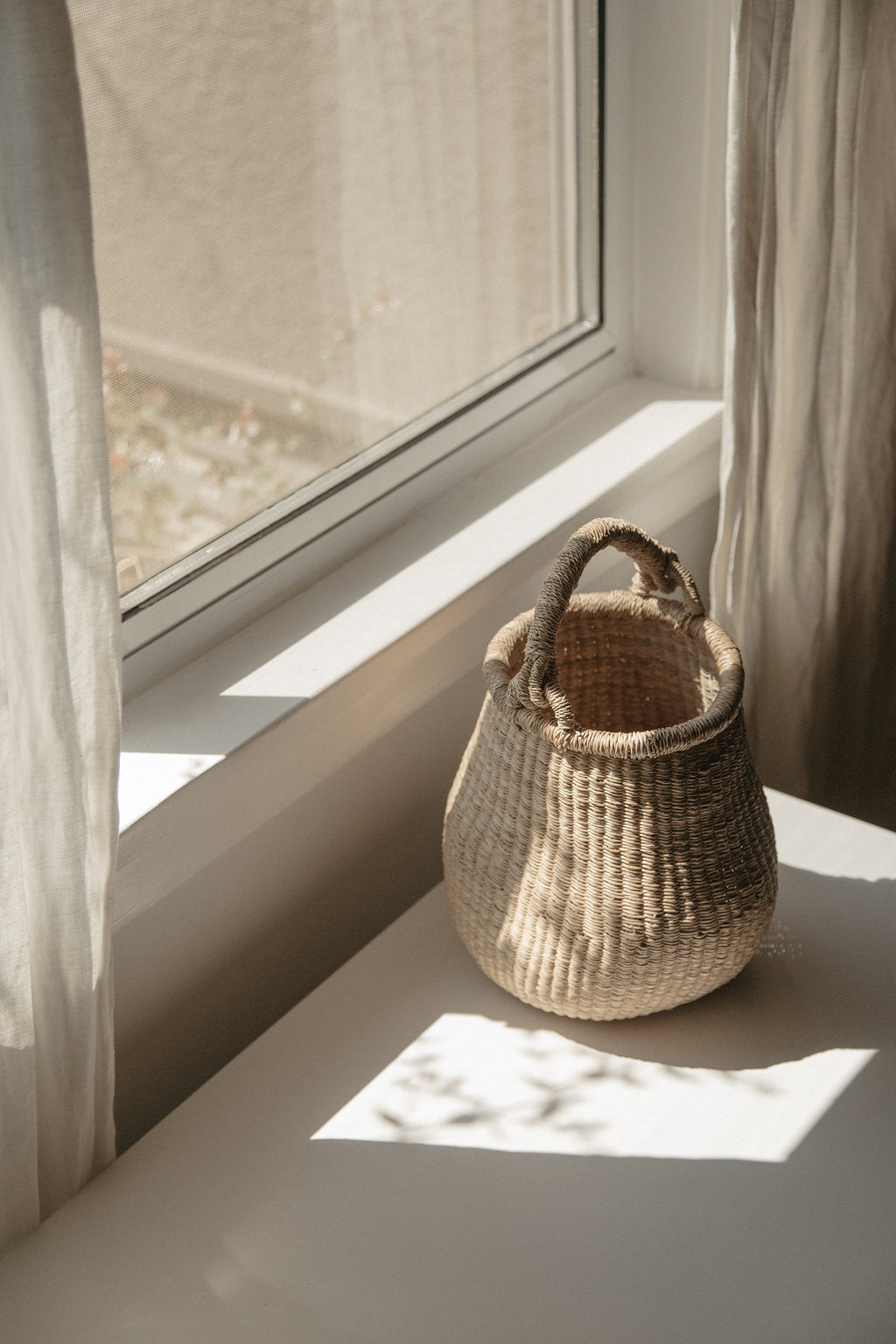 Small handwoven basket with handle, made from natural colored elephant grass, from northern Ghana.