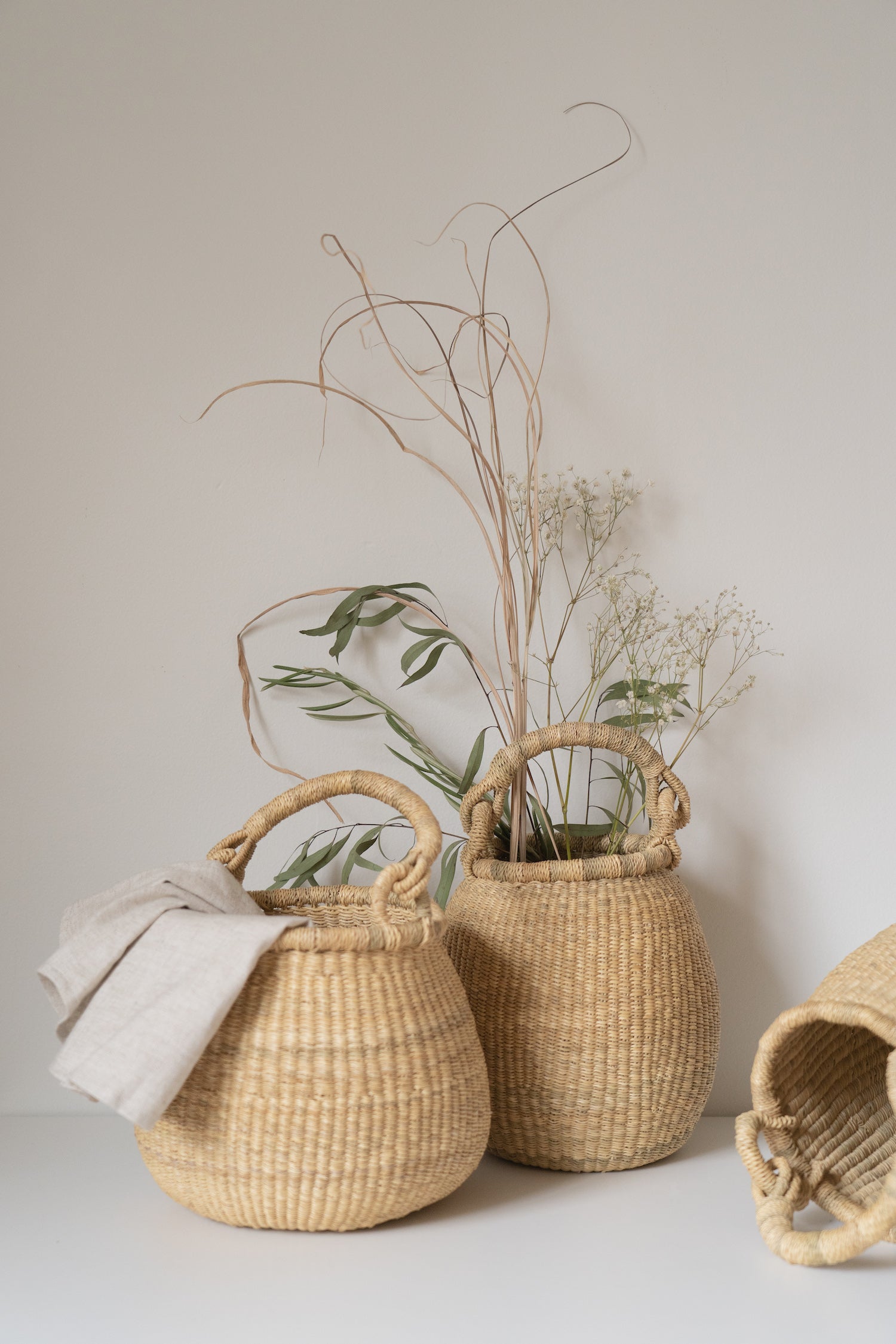 Small handwoven baskets with handles, made from natural colored elephant grass, from northern Ghana.