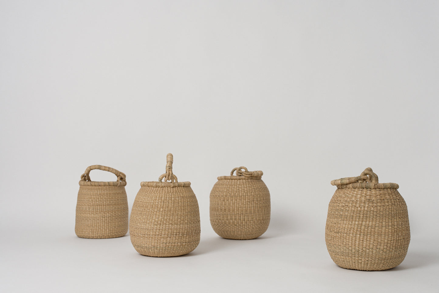 Small handwoven baskets with handles, made from natural colored elephant grass, from northern Ghana.