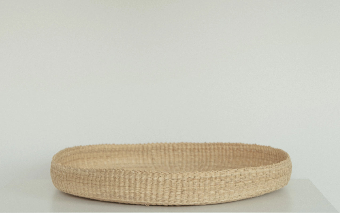 Handwoven round tray made from sustainable natural grass in Ghana.