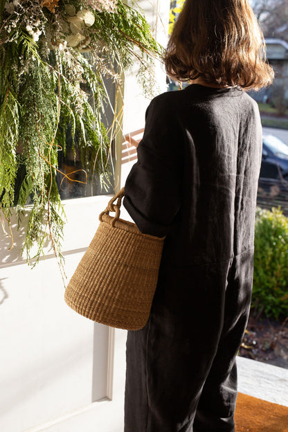 Woman carrying a handwoven basket with handle. Made in northern Ghana from natural colored elephant grass.