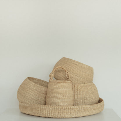 Handwoven round tray made from sustainable natural grass, holding four baskets.