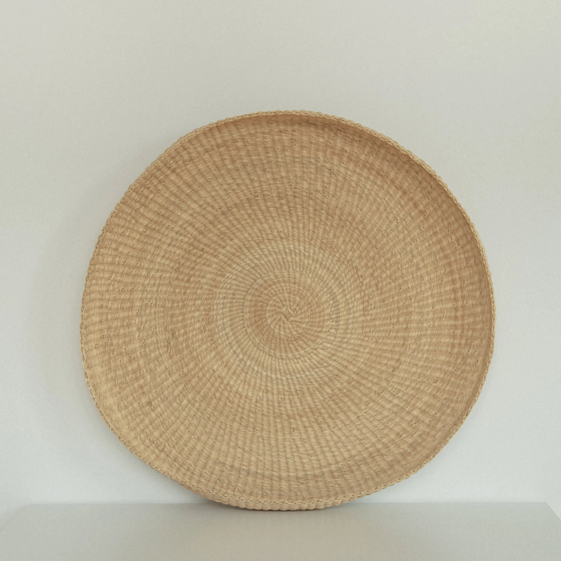 Handwoven round tray made from sustainable natural grass in Ghana.