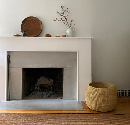 Fireplace shown with large hand woven storage basket. Made in Ghana from local, natural-colored, sustainable materials.