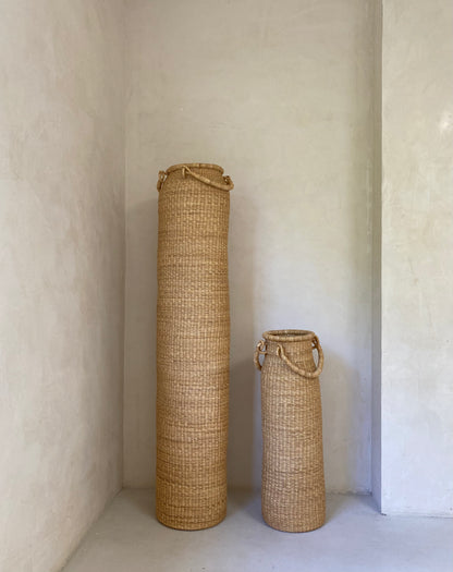 Very tall column-shaped baskets with two handles. More sculpture than storage, these hand woven baskets are made in Ghana from sustainable local grass.