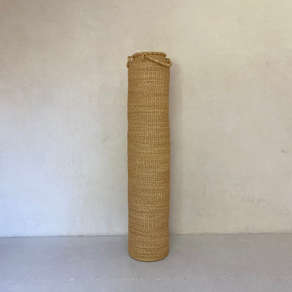 A double height column-shaped basket with two handles. More sculpture than storage, these hand woven baskets are made in Ghana from sustainable elephant grass.